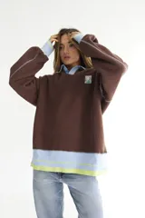 Buzo celeste con cuello polo y puños en rib color verde lima. Tiene un parche con el logo de la marca en el pecho y rayas horizontales en el ruedo.