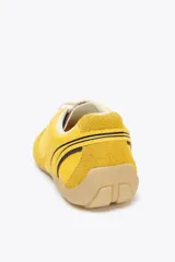 Zapatillas deportivas amarillas con detalles en gamuza y malla, cordones blancos y suela color caramelo.