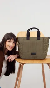 Cartera negra tipo tote bag con diseño capitoneado, doble asa corta y correa larga ajustable. Incluye bolsillos laterales y bolsillo frontal amplio.