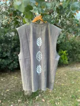 Musculosa gris con estampado de tres hojas blancas en la espalda, de corte amplio y unisex.