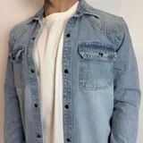 Chaqueta de jean celeste de corte recto, con cuello clásico, cierre frontal con botones metálicos, dos bolsillos con solapa abotonada en el pecho y mangas largas con puños abotonados.