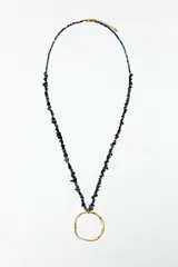 Collar largo con cadena dorada, cuentas de piedras naturales grises y dije circular irregular de acero dorado.