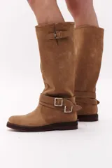 Bota de caña alta color negro, confeccionada en gamuza, con dos correas desmontables con hebillas metálicas.