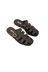 Sandalia plana negra de cuero vacuno con tiras entrelazadas y hebilla lateral metálica.