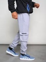 Pantalón de jogging gris con bolsillos cargo laterales y logo de la marca bordado en la pierna.