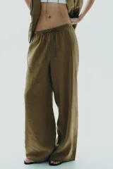 Pantalón palazzo color verde oliva de tejido fluido, tiro medio, cintura elástica ajustable con cordones y bolsillos laterales.