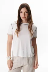 Remera blanca de manga corta con cuello redondo y detalle de costuras en contraste en cuello y mangas.
