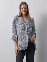 Camisa de mujer estampada con hojas en blanco y negro, cuello con solapa, abertura central con botones, bolsillos aplicados en el delantero y mangas largas con lazo.