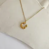 Collar dorado con dije de herradura con diseño calado.