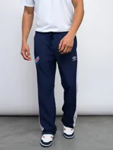 Pantalón deportivo azul marino de nylon con laterales en contraste blanco y rojo. Presenta el escudo del Club Nacional de Football y el logo de Umbro estampados.