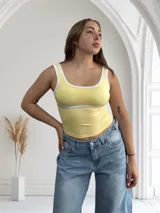 Top amarillo pastel con breteles y borde superior blancos.