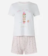 Pijama de dos piezas, compuesto por una remera blanca de manga corta con estampa de surf y un short rosa con lunares negros y cintura elástica.