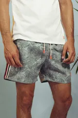 Short de baño con estampado de hojas en tonos grises y celestes, con cordón ajustable en la cintura y detalle de franja lateral con rayas rojas, blancas y negras.
