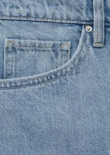 Short de jean celeste claro, de tiro alto, corte recto y largo a medio muslo. Presenta cinco bolsillos y cierre frontal con cremallera y botón.