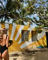 Traje de baño enterizo amarillo con textura arrugada, breteles finos y cierre marrón en el frente.