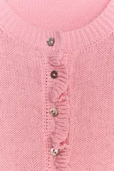 Chaqueta de punto rosa con cuello redondo y manga larga. Detalle de volantes en los bordes y cierre frontal con botones.
