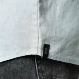 Camisa de lino color gris topo, de corte clásico, con cuello abotonado, manga larga y bolsillo en el pecho.