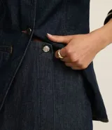 Short pollera de jeans azul oscuro, de cintura alta, con botón metálico en forma de flor y confeccionado con algodón BCI.