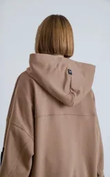 Buzo hoodie marrón de corte oversize, confeccionado en algodón rústico. Tiene capucha forrada, bolsillo tipo bomber con cierre en la manga y bolsillo canguro.