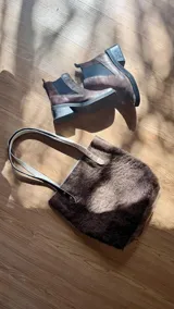 Bolso tote de cuero color marrón oscuro con doble asa larga de cuero y remaches metálicos.
