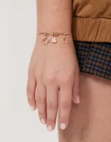 Pulsera dorada de cadena fina con dijes de strass.