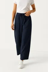 Pantalón de lino color beige, de corte ancho y tiro alto, con bolsillos laterales y cintura elastizada con cordón ajustable.