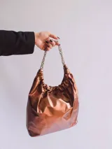 Cartera tipo tote bag negra de cuero con cadena plateada.