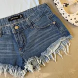 Short de jean de tiro bajo, con ruedo desflecado.
