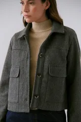 Chaqueta tipo abrigo color gris, con botones frontales y bolsillos laterales.