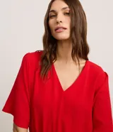 Vestido evasê midi color rojo, confeccionado en tejido airflow con escote en V, mangas cortas amplias y cintura elastizada. Material más sostenible: poliéster certificado GRS.