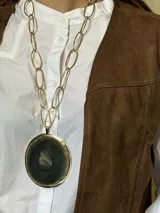 Collar largo con cadena de eslabones dorados y dije circular de ágata verde oscuro con borde dorado.