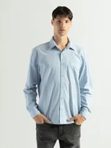 Camisa de manga larga color verde oliva, confeccionada en algodón. Tiene corte clásico, bolsillo en el lado izquierdo del pecho y cierre con botones.