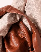 Bolso marrón oscuro de cuero sintético con forma ovalada y asa corta.