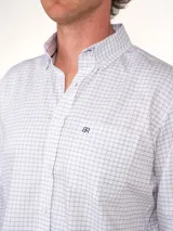 Camisa de vestir de hombre, corte clásico, con estampado a cuadros en tonos rosa y celeste. Tiene cuello abotonado, bolsillo en el pecho y mangas largas.