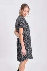 Vestido corto de manga corta y cuello mao con abertura en V, de corte suelto y estampado floral o abstracto en tonos beige sobre fondo negro.