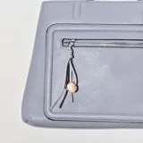 Cartera celeste de simil cuero, con un diseño práctico y moderno, y un bolsillo frontal con cierre.