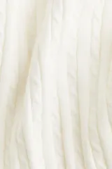 Buzo blanco de punto con escote redondo pronunciado y tejido en punto trenzado vertical. Presenta remates acanalados en cuello, puños y bajo.