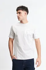 Remera gris de manga corta con cuello redondo y estampado tipográfico en el frente.