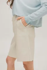 Bermuda color beige de cuerina, tiro alto, con cierre y botón invisible.