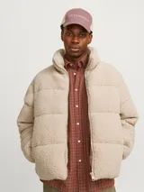 Campera puffer color beige de tela tipo teddy, con cuello alto, cierre frontal con cremallera, bolsillos laterales y puños elásticos.