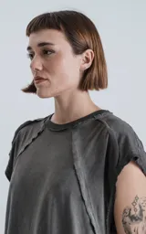 Remera gris con cuello redondo y sisas amplias, con recortes en delantero y mangas y efecto gastado.