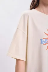 Remera manga corta oversize color crudo con estampa de sol y texto 'Le Soleil' en naranja y celeste.