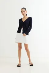 Cárdigan negro de tejido de punto fino con escote en V, cierre frontal con botones dorados y mangas largas con puños ajustados.