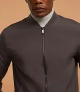 Campera bomber de poliéster color gris oscuro, con cuello alto, cierre frontal con cremallera, bolsillos laterales, mangas largas con puños ajustados y bajo con ajuste elástico.