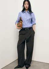 Camisa de manga larga con cuello camisero, diseño recto y cierre frontal de botones. Presenta un patrón de rayas verticales finas en tonos azul claro y blanco.