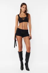 Top negro de gabardina elastizada con cordones cruzados en el frente y cierre metálico en la espalda.