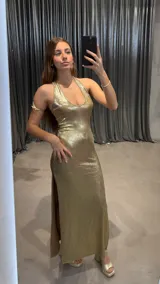 Vestido largo dorado con escote halter y abertura lateral en la falda.