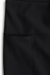 Leggings deportivas negras de tiro alto con cintura ancha y bolsillo abierto en la parte exterior de las piernas. Confeccionadas en tejido funcional ShapeMove™ con detalles reflectantes.