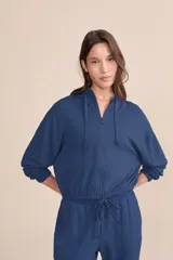 Campera azul de moletón con capucha ajustable y cierre frontal con cremallera. Diseño con recorte en las mangas y corte relajado.