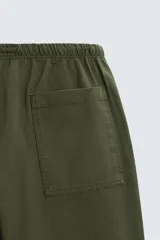 Pantalón verde militar de corte carrot fit, confeccionado en tejido de algodón. Cuenta con cintura elástica ajustable con cordón, bolsillos frontales y un bolsillo trasero de plastrón.